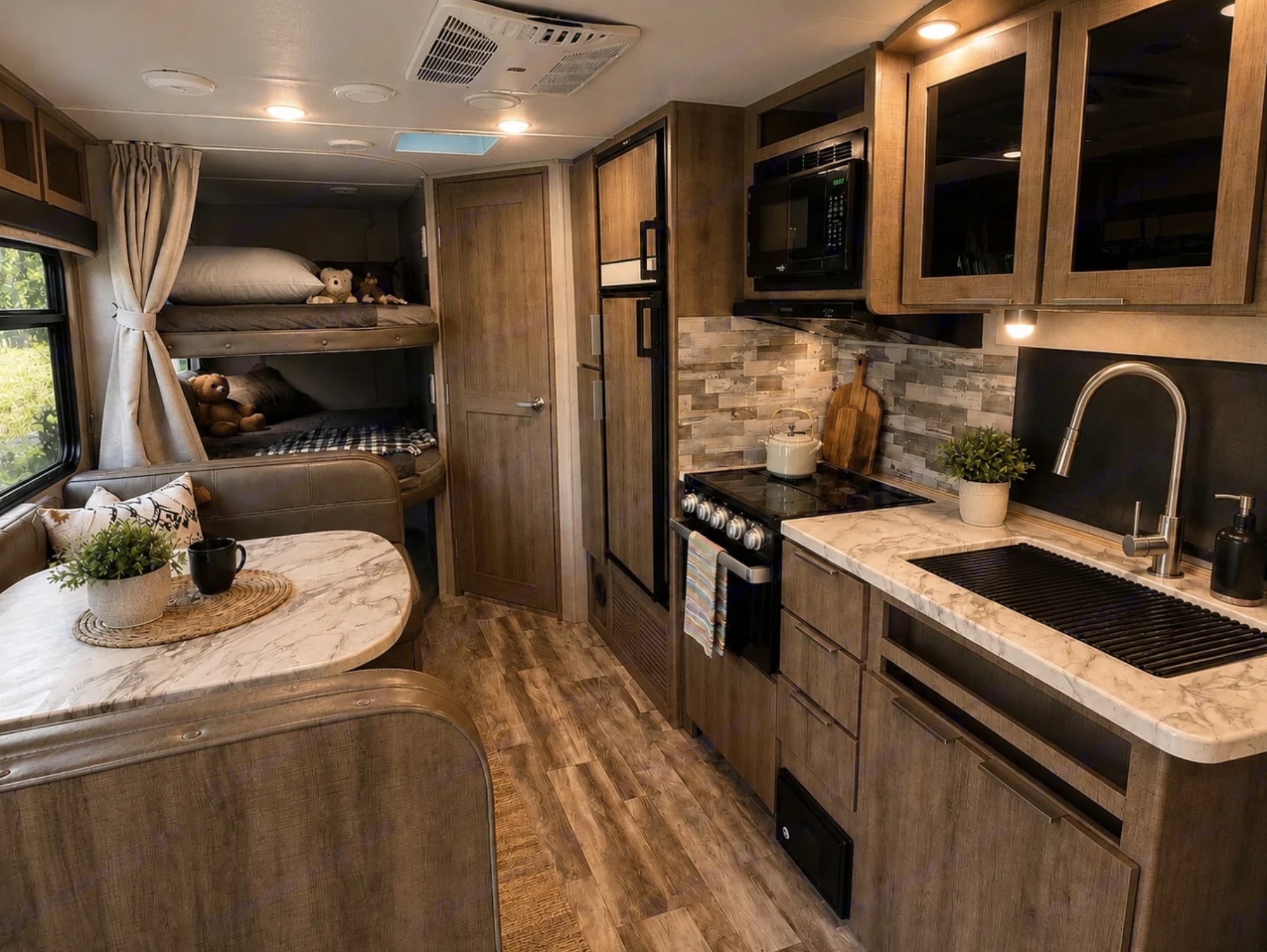 Full galley kitchen with stove, microwave and sink beside a marble dinette and bunk beds